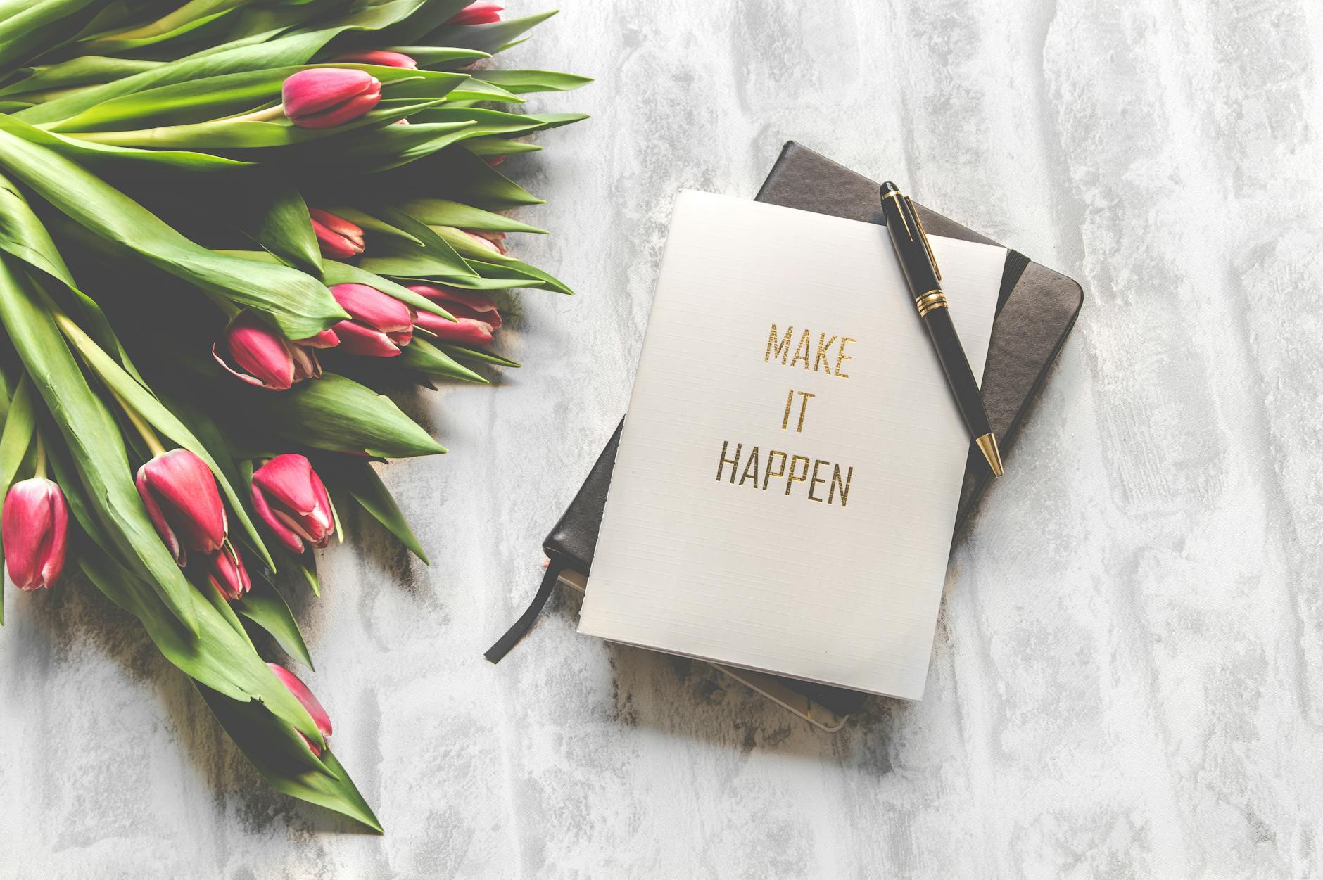 flowers next to book "make it happen" on mable