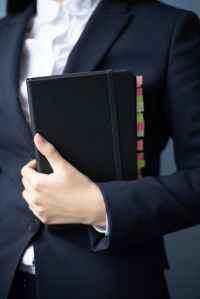 blue suit with white shirt person holding black notebook with tabs